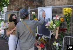 People place flowers alongside a photo of Anglican Archbishop Desmond Tutu at the St. George's Cathedral in Cape Town, South Africa, Dec. 26, 2021.