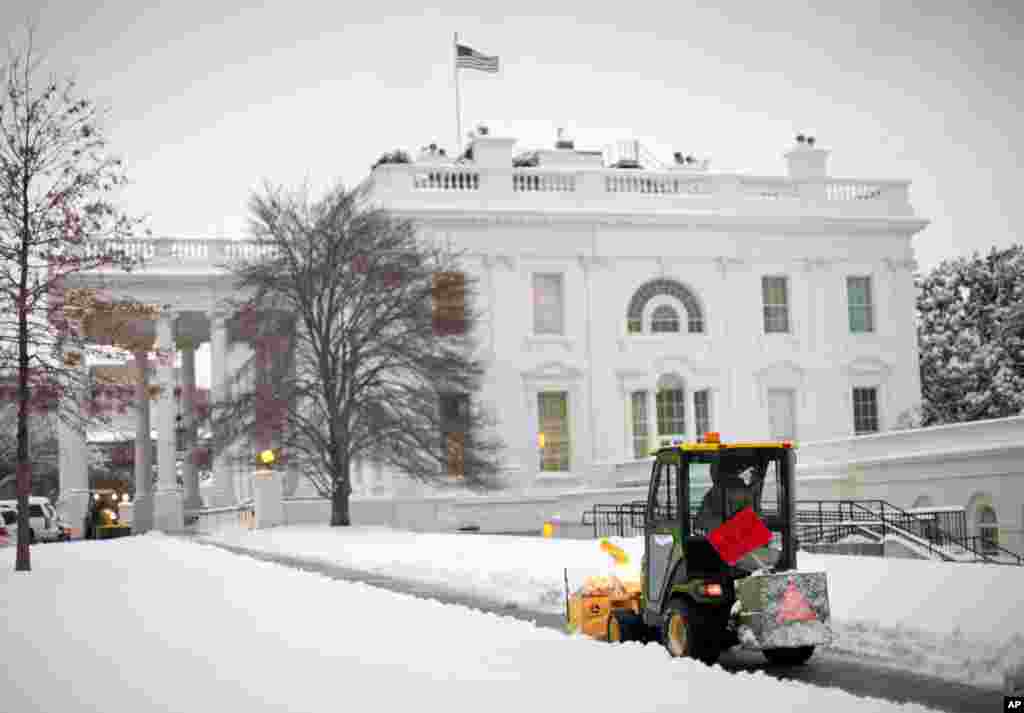 Petugas membersihkan jalur pejalan kaki menuju Gedung Putih setelah salju yang turun sepanjang malam menghantam wilayah Washington, D.C., 17 Maret 2014.