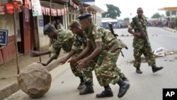 Des soldats roulent un roc placé par des manifestants à Cibitoke, un quartire de Bujumbura, Burundi, vendredi 22 mai 2015.