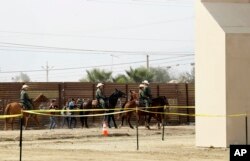 FILE - A group of people are detained by Border Patrol agents on horseback after crossing the border illegally from Tijuana, Mexico, near prototypes for a border wall, right, being constructed in San Diego, California, Oct. 19, 2017.