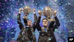 In this Saturday, July 27, 2019 photo, provided by Epic Games, Emil "Nyhrox" Bergquist Pedersen, of Norway, left, and David "Aqua" Wang, of Austria, hold up their trophies after winning the Fortnite World Cup duo championship in New York. (Epic Games via