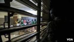 A man looks through a window as votes are about to be tallied at a polling station in Ouagadougou, Burkina Faso, November 29, 2015. (Photo - E. Iob/VOA)