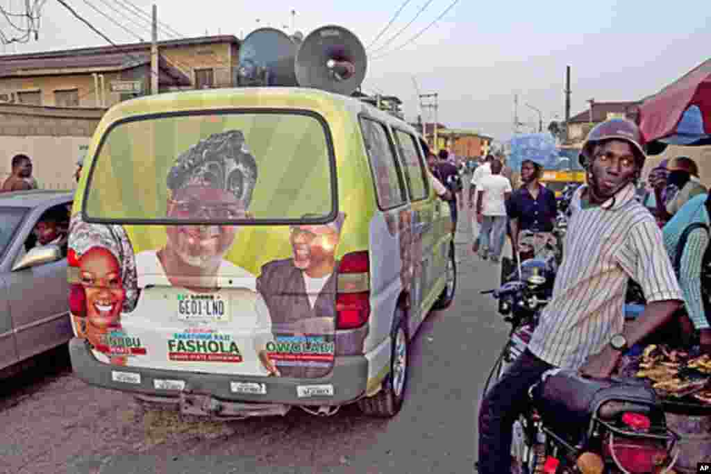 A campaign van for Lagos state governor drives past a motorcyclist in Lagos, Nigeria, March 9, 2011