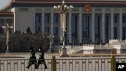 戴着口罩的中国武警士兵在北京人大会堂前空旷的天安门广场上行走。（2020年2月23日）