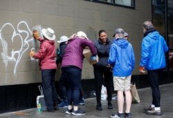 Pejalan kaki tawarkan kopi kepada relawan yang membersihkan grafiti di Seattle, Washington.