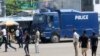 FILE - People walk past a police truck in DRC's capital Kinshasa, Dec. 19, 2016. Military and police units were deployed across the city amid fears of unrest on the last official day of President Joseph Kabila's second term.