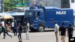 FILE - People walk past a police truck in DRC's capital Kinshasa, Dec. 19, 2016. Military and police units were deployed across the city amid fears of unrest on the last official day of President Joseph Kabila's second term.