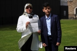 Fatima Boudchar, wife of Libyan dissident Abdel Hakim Belhaj, stands with their son Abderrahim, as she holds a letter of apology from British Prime Minister Theresa May outside the Houses of Parliament in Westminster, London, Britain, May 10, 2018.