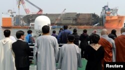 Family members of victims onboard the sunken ferry Sewol and religious people look on during a memorial ceremony at the sea off Jindo, South Korea, March 28, 2017. 