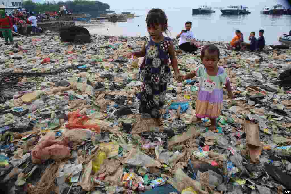 Children walk on garbage during an annual Lampung bay clean-up event in the Sukaraja village in the Bumi Waras subdistrict of Bandar Lampung, Indonesia.