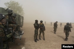 FILE - Cameroonian soldiers stand guard amidst dust kicked up by a helicopter in Kolofata, Cameroon, March 16, 2016. Part of a multinational force, the soldiers have intensified their fight against Boko Haram militants.