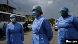 Trabajadores de salud esperan en la calle antes de comenzar un programa de extensión de salud puerta a puerta en medio del brote de la enfermedad por coronavirus, en Guayaquil, Ecuador, el 14 de abril de 2020.