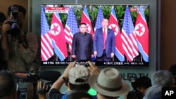 FILE - People watch a TV screen showing U.S. President Donald Trump, right, meeting with North Korean leader Kim Jong Un in Singapore during a news program at the Seoul Railway Station in Seoul, South Korea, June 12, 2018.