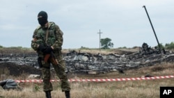 Pemberontak pro-Rusia menjaga lokasi jatuhnya pesawat Malaysia Airlines dekat desa Hrabove, Ukraina timur (19/7). (AP/Evgeniy Maloletka)