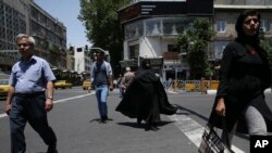 Des piétons iraniens traversent la rue Jomhouri-e-Eslami (République islamique) au centre-ville de Téhéran, en Iran, le 9 juin 2018.
