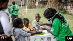 Yon enfimyè ki t ap montre kèk timoun kijan pou yo byen lave men yo nan antre Lopital Mbagathi nan vil Nayewobi, kapital Kenya, nan dat 18 mas 2020.