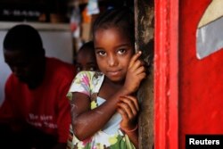 Une petite fille regarde derrière une porte à Dakar, au Sénégal, le 31 janvier 2011.