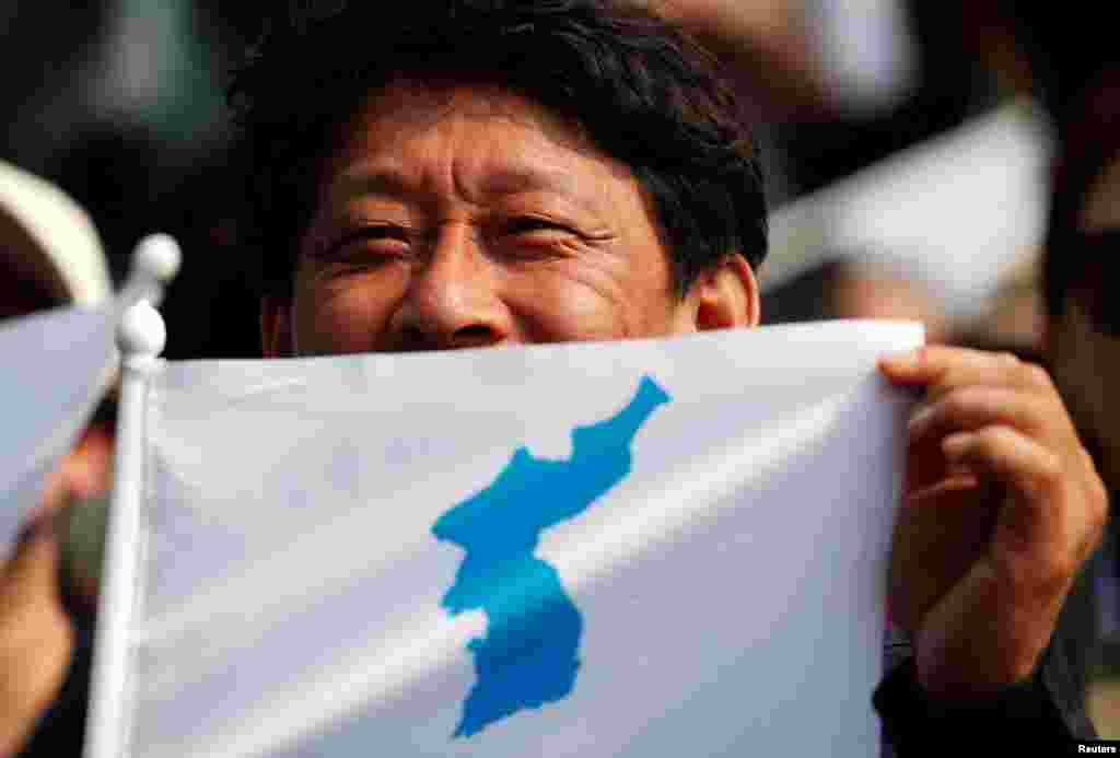 A man displays the Korean unification flag as he watches a news report on the inter-Korean summit, near the demilitarized zone separating the two Koreas, in Paju, South Korea, April 27, 2018.