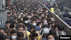 FILE - Morning commuters wait in line at the Tiantongyuan subway station on a smoggy day after the city issued its first ever "red alert" for air pollution, in Beijing, China, Dec. 8, 2015.