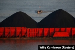 Seorang pria berdiri di atas kapal saat tongkang batu bara mengantre untuk ditarik di sepanjang Sungai Mahakam di Samarinda, Kalimantan Timur, 31 Agustus 2019. (Foto: REUTERS/Willy Kurniawan)