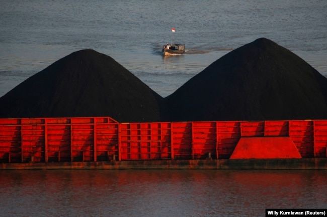 Seorang pria berdiri di atas kapal saat tongkang batu bara mengantre untuk ditarik di sepanjang Sungai Mahakam di Samarinda, Kalimantan Timur, 31 Agustus 2019. (Foto: REUTERS/Willy Kurniawan)