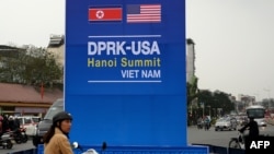 Seorang pengendara sepeda motor melintasi papan promosi terkait pertemuan puncak mendatang antara Presiden AS, Donald Trump, dan Pemimpin Korut, Kim Jong Un, di sebuah jalan yang sibuk di Hanoi, 19 Februari 2019 (Photo: Nhac Nguyen/AFP)