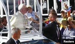 Pope Francis kisses a child as he arrives to lead a mass for Catholic faithful in the city of Holguin, Cuba, Sept. 21, 2015.