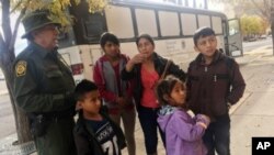 Una familia migrante centroamericana espera afuera del albergue Casa de la Anunciación, en El Paso, Tejas, el 29 de noviembre de 2018, después que un agente de Inmigración y Aduanas de EE.UU., los llevó hasta allá.