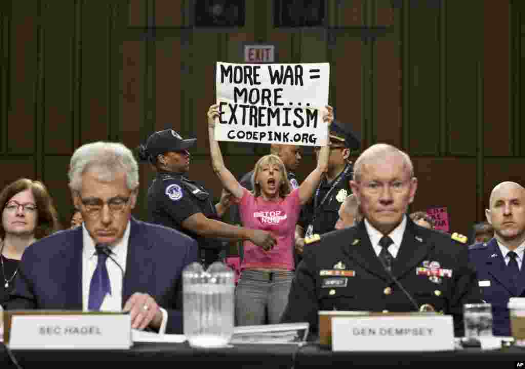 Para aktivis anti-perang &#39;CodePink&#39; menginterupsi saat Menhan AS Chuck Hagel dan pemimpin militer AS Jenderal Martin Dempsey memberikan keterangan di Gedung Kongres AS di Washington DC.