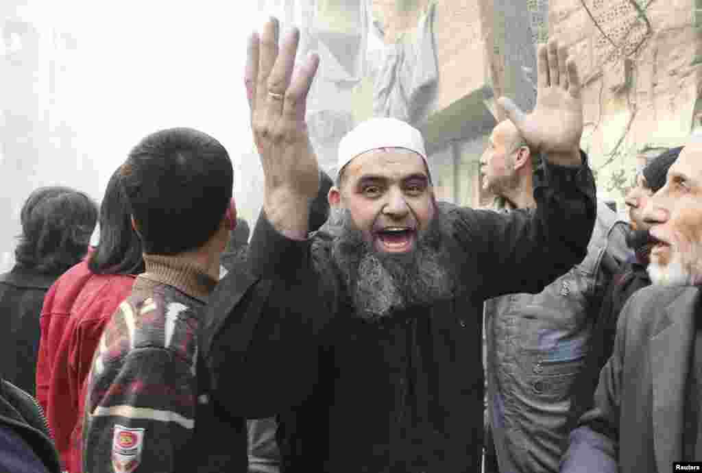 A man waves his arms at a site hit by what activists said was a barrel bomb dropped by forces loyal to President Bashar Assad in the al-Shaar district, Aleppo, Feb. 9, 2014.&nbsp;