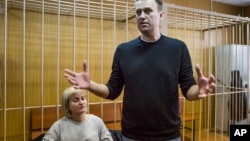 Russian opposition leader Alexei Navalny gestures while speaking, as his lawyer Olga Mikhailova listens, in court in Moscow, Russia, March 27, 2017. 