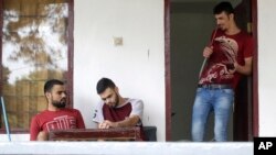 FILE - Iraqi asylum seeker Ayman, right, chats with his brother, left, and friend, center, during an interview with The Associated Press at temporary home in Puncak, West Java, Indonesia, Jan. 31, 2017.