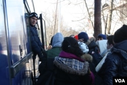 Refugees board a bus to leave Presevo for Serbia's northern border with Croatia, Jan. 19, 2016. (P. Walter Wellman/VOA)