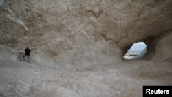 FILE - A man uses a pick to break rocks and get sand in a sand mine in Haiti, March 21, 2018. Sand mining is a growing business worldwide, but it is blamed for a wide range of environmental issues. A dispute over sand mining in Gambia has left two people dead.