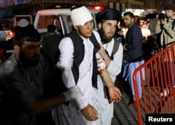 Afghan men carry an injured person to a hospital after a suicide attack in Kabul, Afghanistan, Nov. 20, 2018.