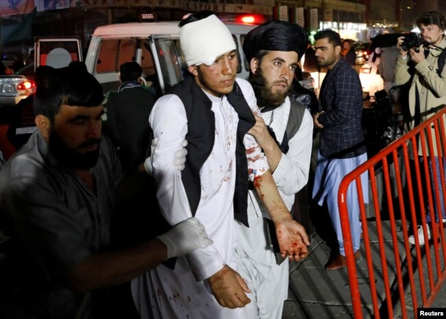 Afghan men carry an injured person to a hospital after a suicide attack in Kabul, Afghanistan, Nov. 20, 2018.