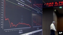 A man walks behind screens showing a graph of stocks at the Athens Stock Exchange, in Athens, October 24, 2011.