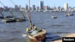 FILE - A fisherman cleans his boat beneath Maputo’s skyline in Mozambique on Aug. 15, 2015. A member of the Renamo party was killed Oct. 8, 2016, on a Maputo beach.