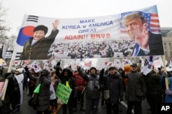 A banner showing pictures of impeached South Korean President Park Geun-hye and U.S. President Donald Trump is displayed as supporters of Park wave flags of the United States and South Korea during a rally opposing her impeachment in Seoul, South Korea,
