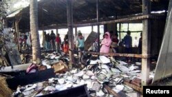 People look at burnt textbooks after a primary school which was supposed to be used as a polling booth was set on fire, in Feni, Bangladesh, Jan. 4, 2014. 