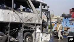 An Iraqi army soldier inspects a destroyed bus in Baghdad, 04 Dec 2010