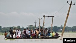 Villagers use a boat to cross a flooded road at Asigarh village in Morigaon district in the northeastern state of Assam, India, July 4, 2017.