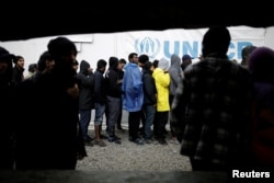 Refugees and migrants line up to receive their lunch provided by the Greek authorities, at a makeshift camp next to the Moria camp on the island of Lesbos, Greece, Nov. 30, 2017.