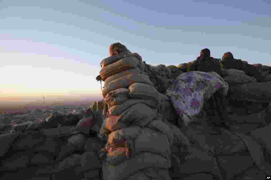 A Kurdish fighter, known as a Peshmerga, lies underneath a blanket, overlooking the town of Sinjar, Iraq. Peshmerga forces, supported by U.S. airstrikes and ground spotters, battled Friday to seize Sinjar from Islamic State militants who have controlled it for more than a year.