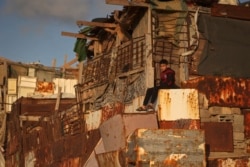 FILE - A Palestinian boy sits outside his makeshift home on the beach at the al-Shati camp for Palestinian refugees in Gaza City, Dec. 21, 2021.