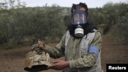 A Civil Defense member carries a damaged canister in Ibleen village from what activists said was a chlorine gas attack, on Kansafra, Ibleen and Josef villages in Syria.