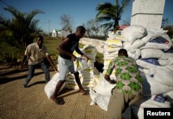 Workers offload food aid from a South African National Defense Force helicopter in the aftermath of Cyclone Idai in Buzi, near Beira, Mozambique, March 25, 2019.