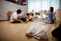 Lee Seung-yoon, his wife Che Min-hee and their son Lee Ji-sung set up camping gear as they prepare for a staycation at their home amid the coronavirus pandemic, in Seoul, South Korea, August 22, 2020. (REUTERS/Kim Hong-Ji)