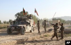 FILE - Afghan national army soldiers stand near the body of a Taliban fighter killed in Ghazni province, eastern Afghanistan, Sept. 14, 2015.