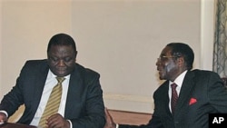 Zimbabwean President Robert Mugabe, right, chats to Prime Minister Morgan Tsavangirai during their end of year press conference at State House in Harare, saying they were dispelling rumors of disunity in the Government of National Unity, December 20, 2010